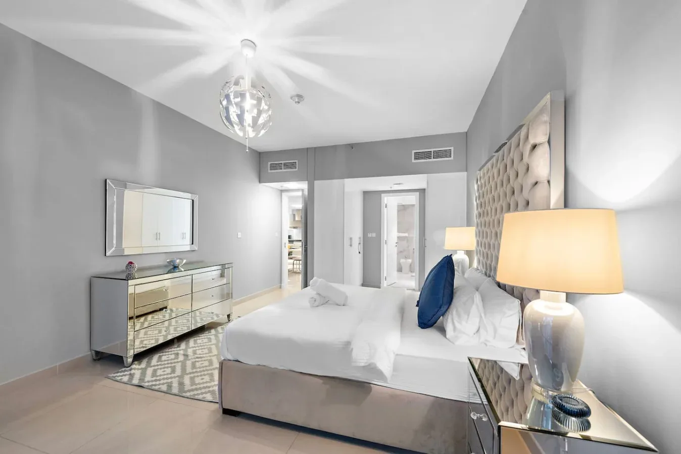 Un dormitorio con cama, cómoda con espejo y lámpara de mesita.