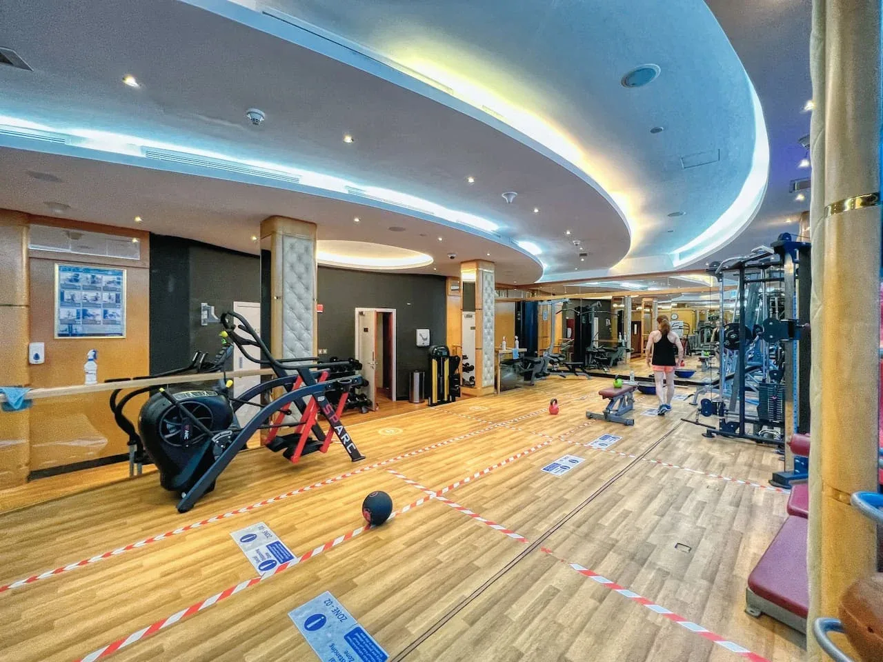 Un gimnasio con máquinas de ejercicio y un amplio suelo de madera.