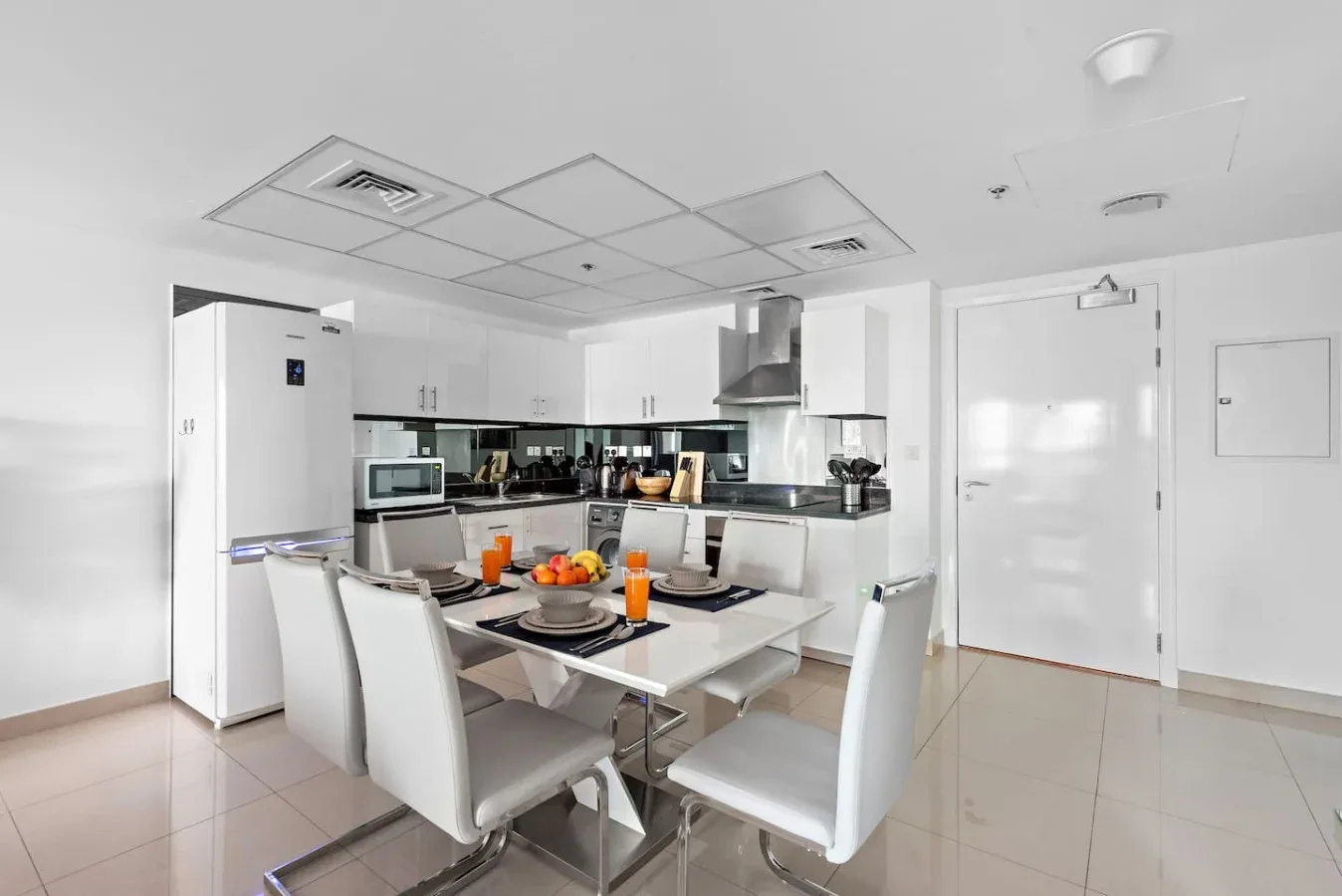 Un comedor luminoso con la mesa puesta junto a una cocina compacta.