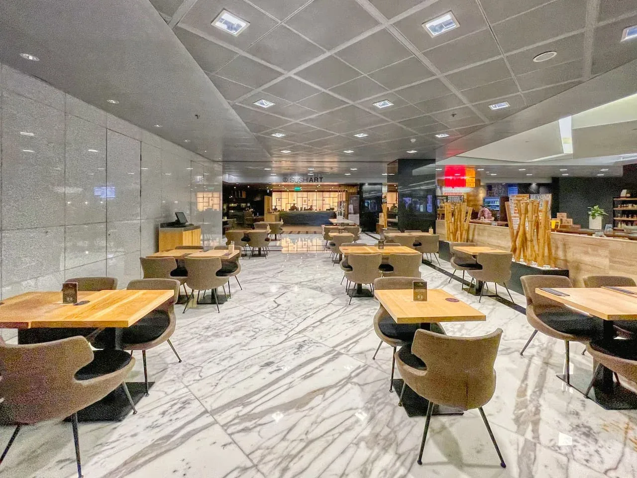 Un amplio comedor con mesas y asientos distribuidos por una sala luminosa.