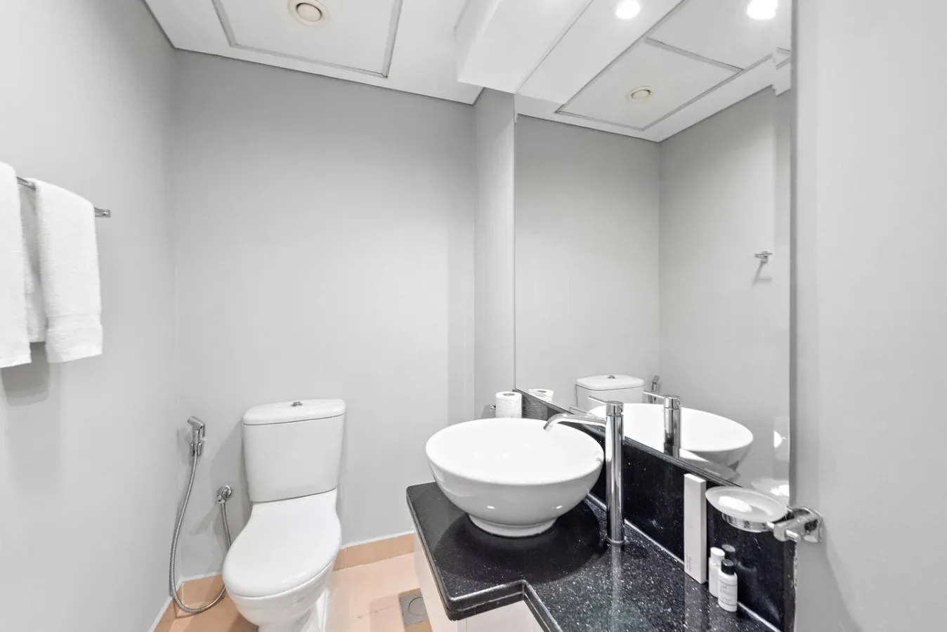 Un baño luminoso con inodoro, lavabo y un espejo grande.
