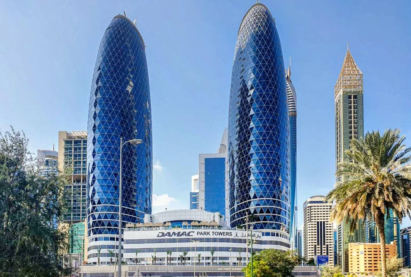 El horizonte urbano muestra dos altas torres curvas de vidrio azul y edificios cercanos.