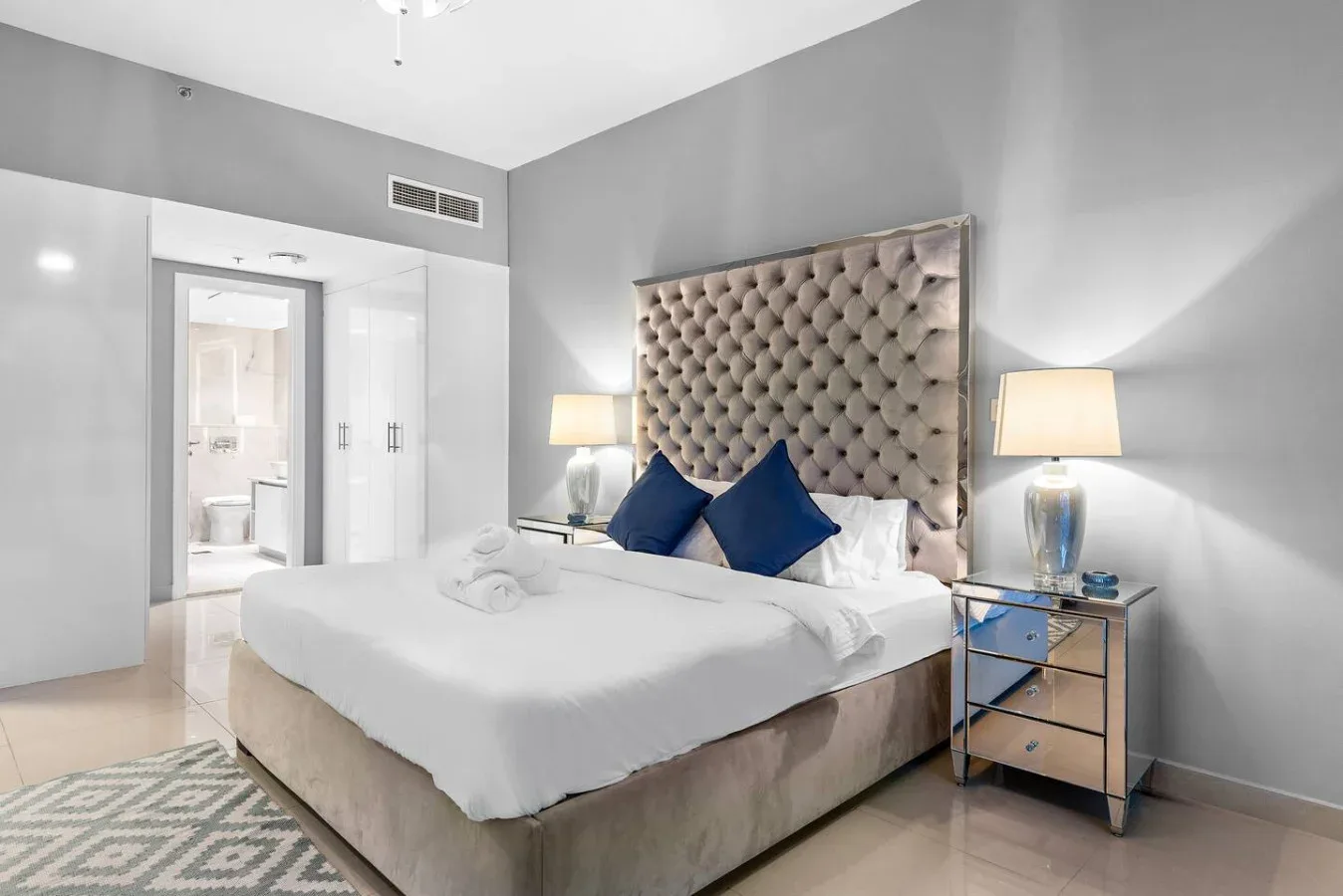Un dormitorio con una cama bien tendida y un cabecero acolchado.