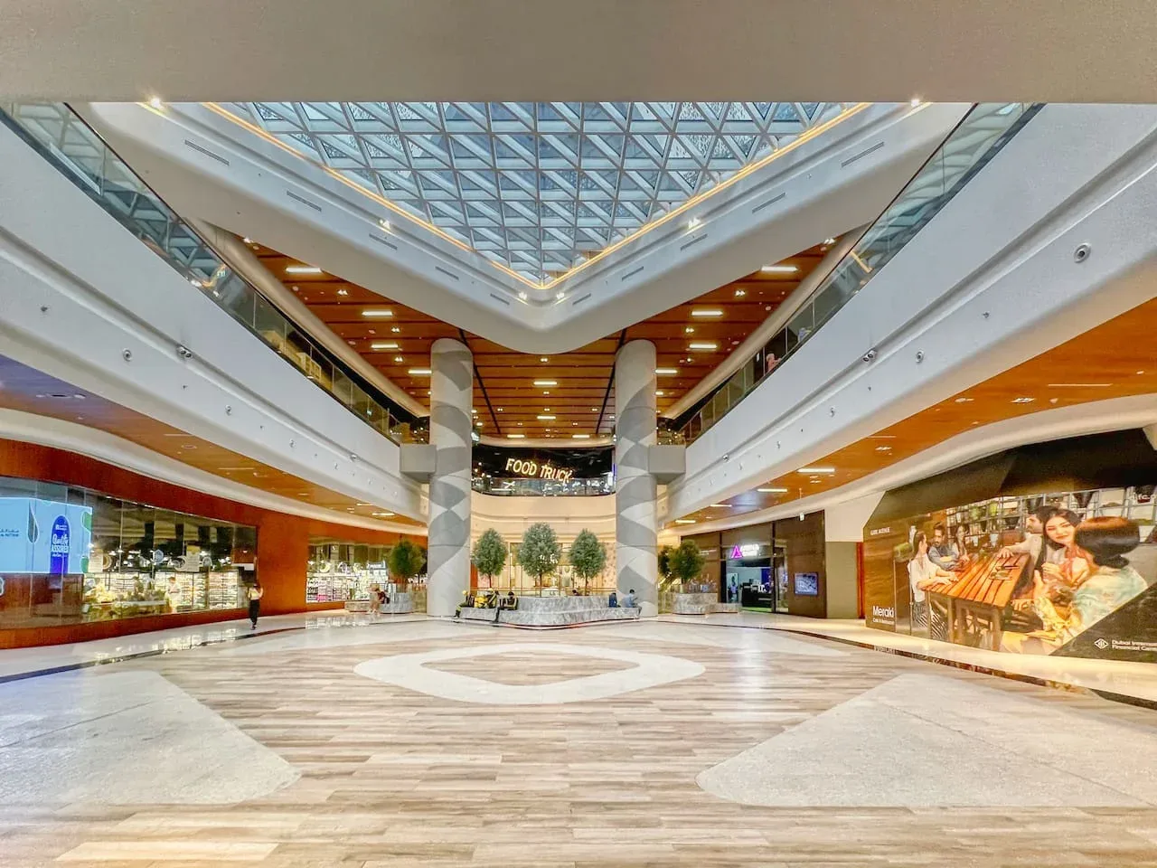 Un amplio atrio de centro comercial con techo de vidrio y tiendas.