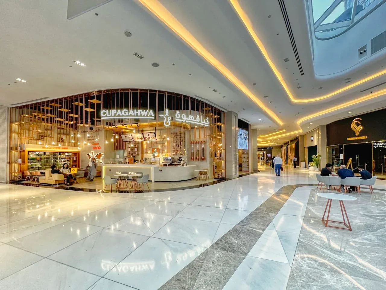Un pasillo de centro comercial con una cafetería y una zona de asientos.