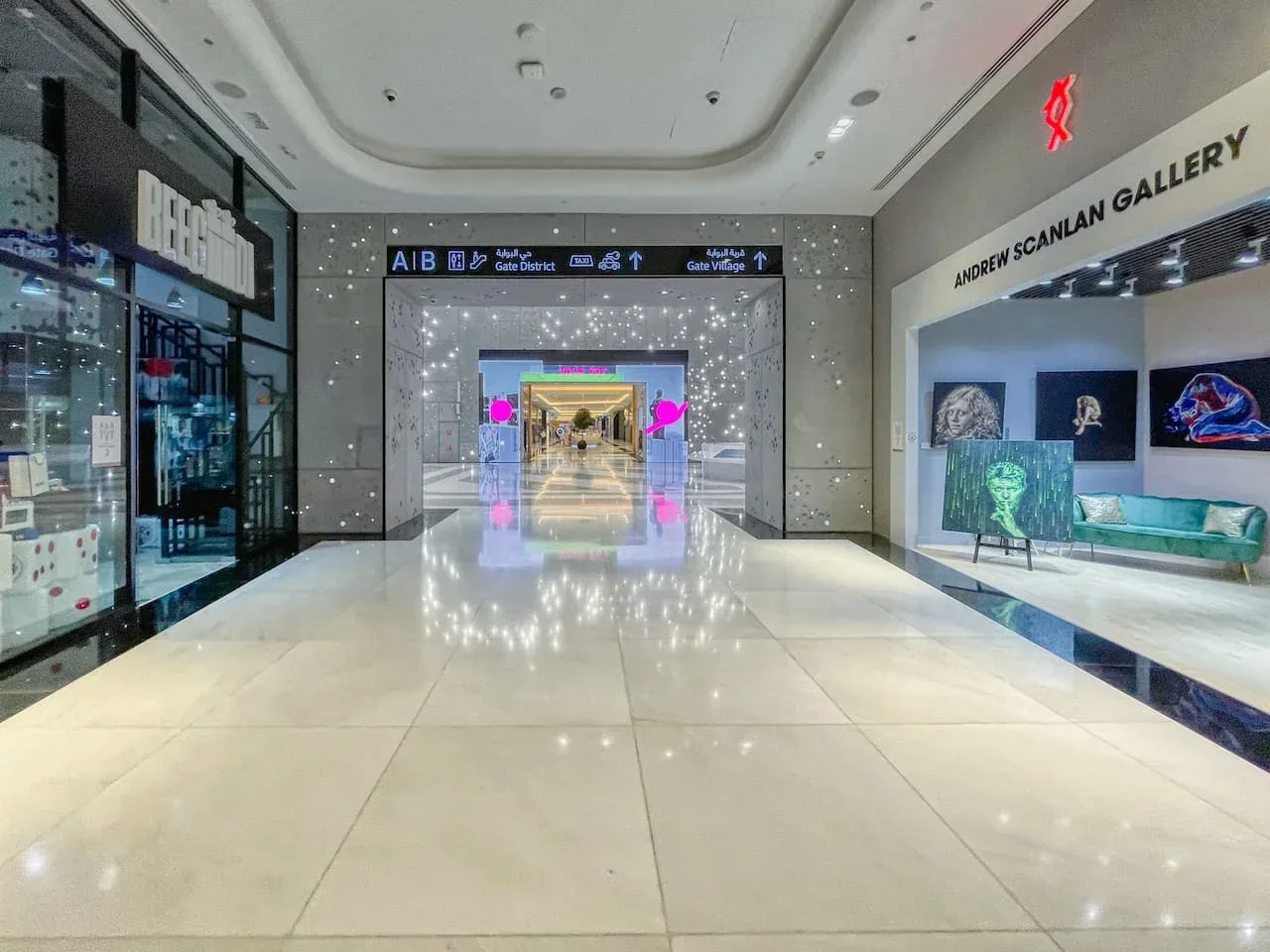 Un pasillo de centro comercial iluminado con tiendas y una galería de arte.