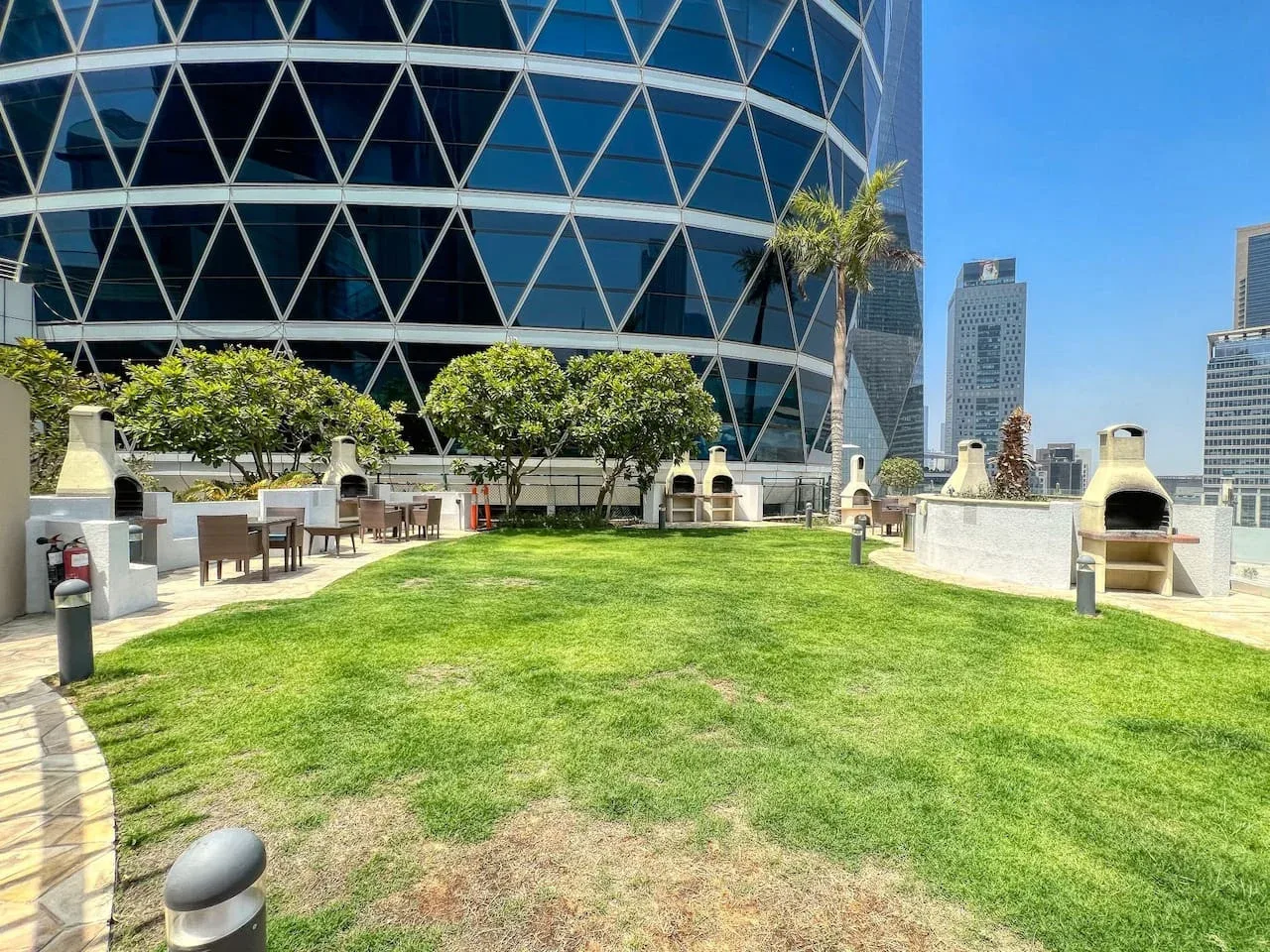 Una terraza en la azotea con césped, asientos al aire libre y parrillas integradas.