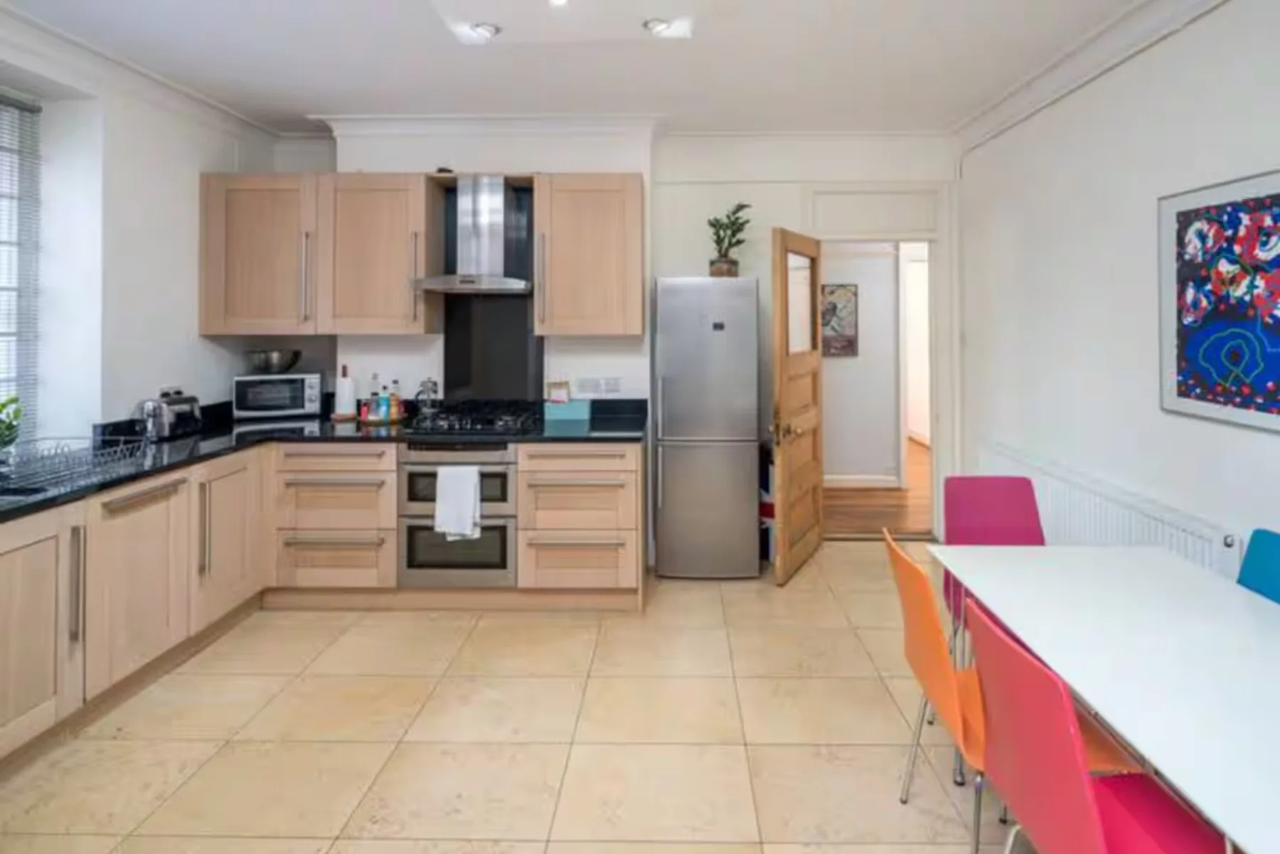 A bright kitchen with light wood cabinets and a dining table.
