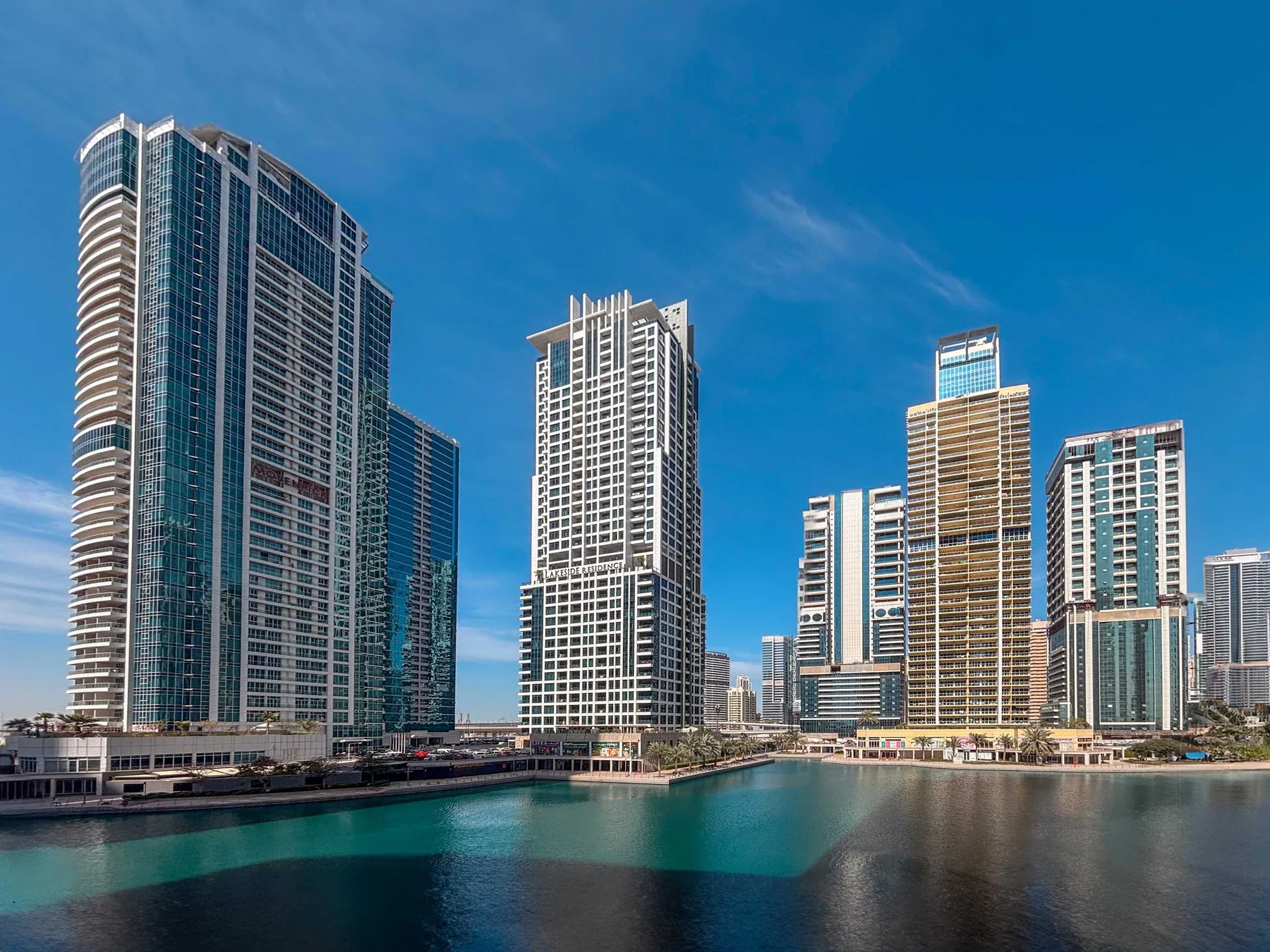 Edificios modernos de gran altura bordean el agua bajo un cielo azul despejado.