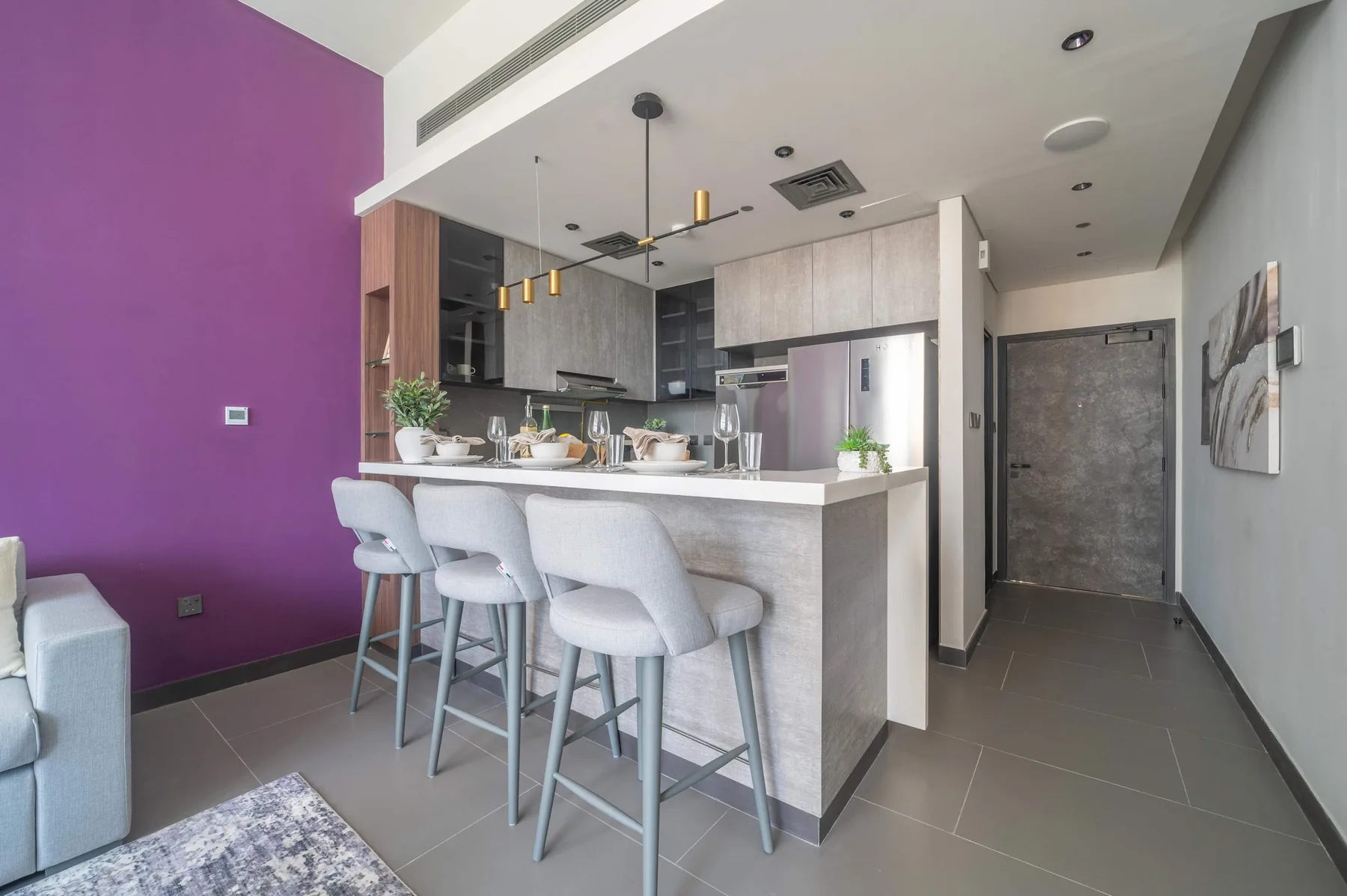 Una cocina abierta con zona de comedor, una barra y taburetes.