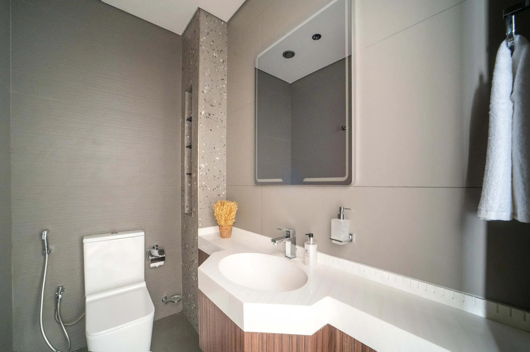Un baño moderno con lavabo blanco, inodoro y espejo de pared.