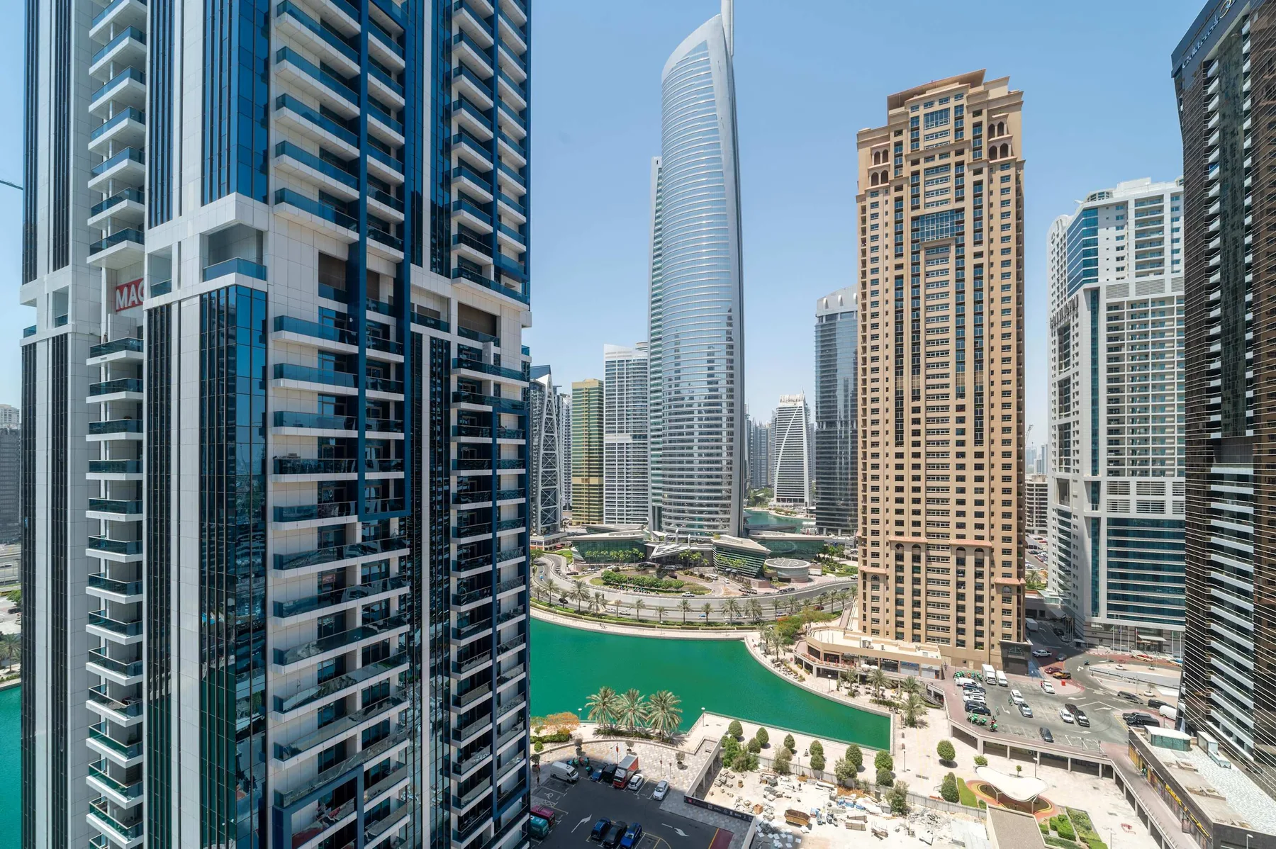 Un paisaje urbano de edificios modernos de gran altura junto a un canal de agua turquesa.