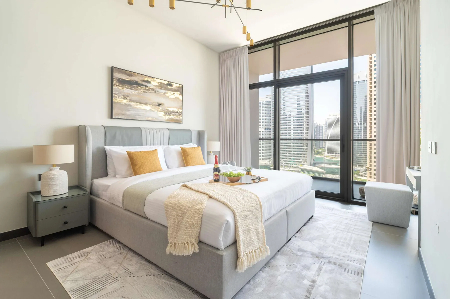 Un dormitorio luminoso con una cama grande junto a ventanas de piso a techo.