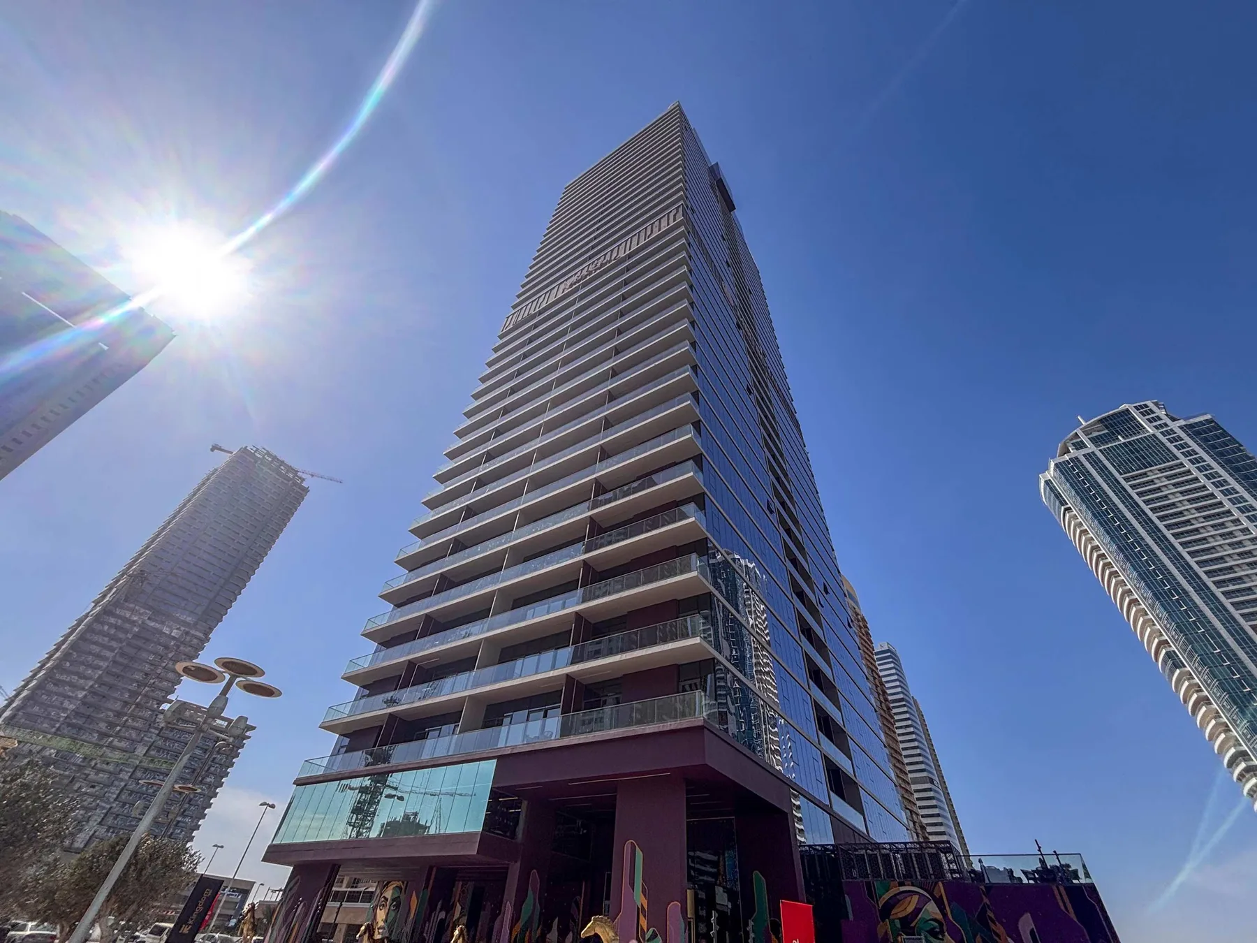Un edificio alto y moderno se alza bajo un cielo azul despejado.