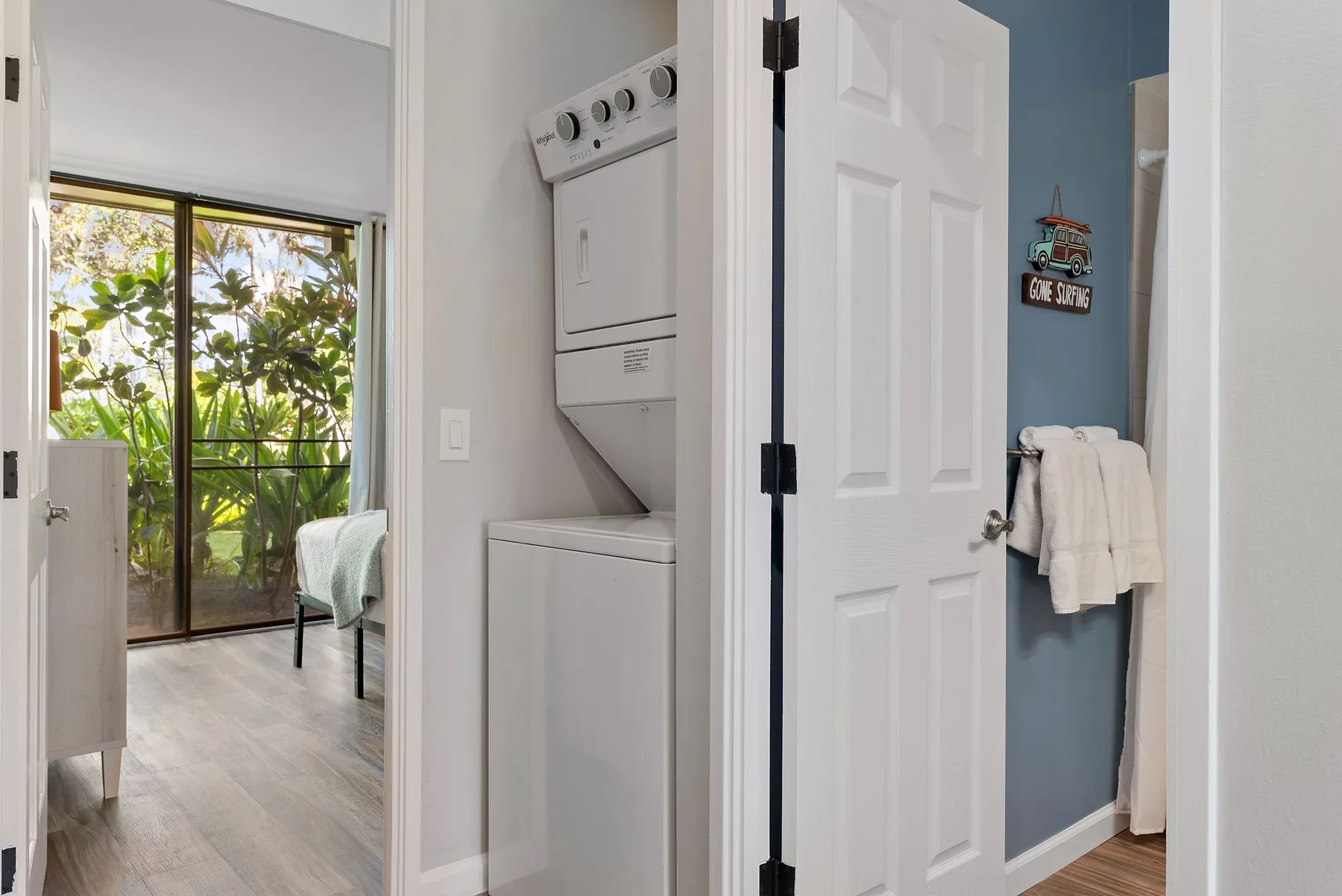 A laundry area with a stacked washer and dryer beside an open bathroom doorway.