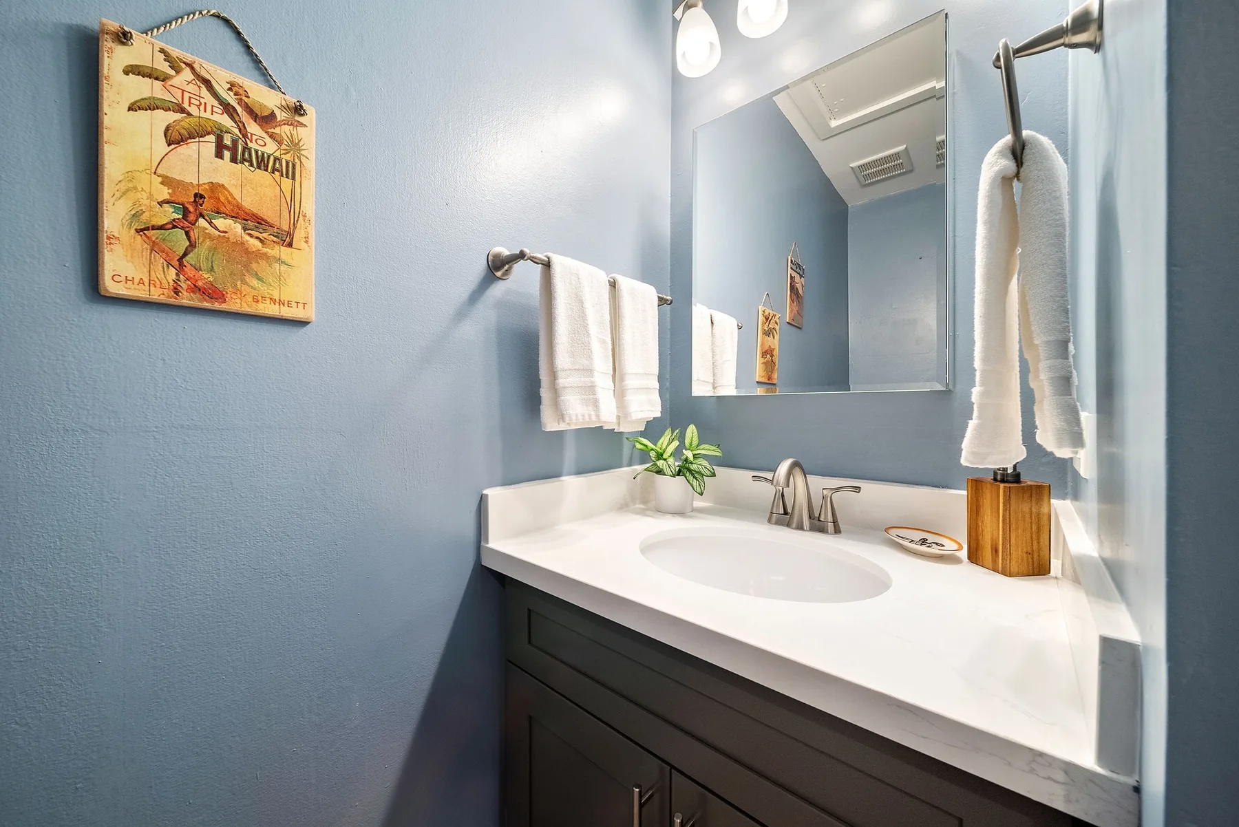 A bathroom vanity with a wide mirror and towels hanging nearby.