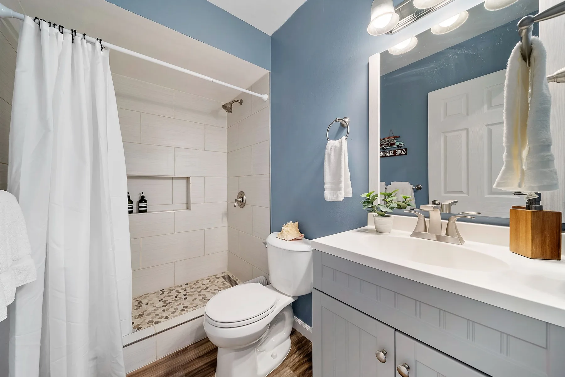 A bathroom with a tiled shower, toilet, and sink vanity.