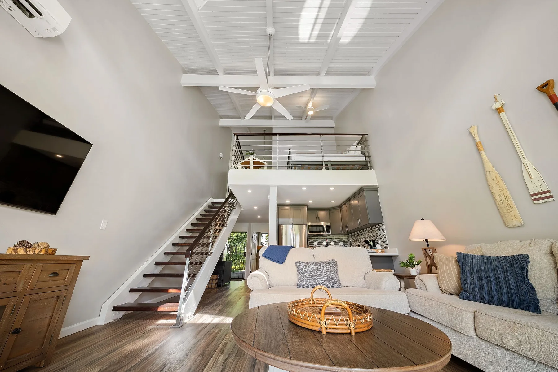 Una sala luminosa con sofá seccional y una escalera que conduce a un nivel superior.
