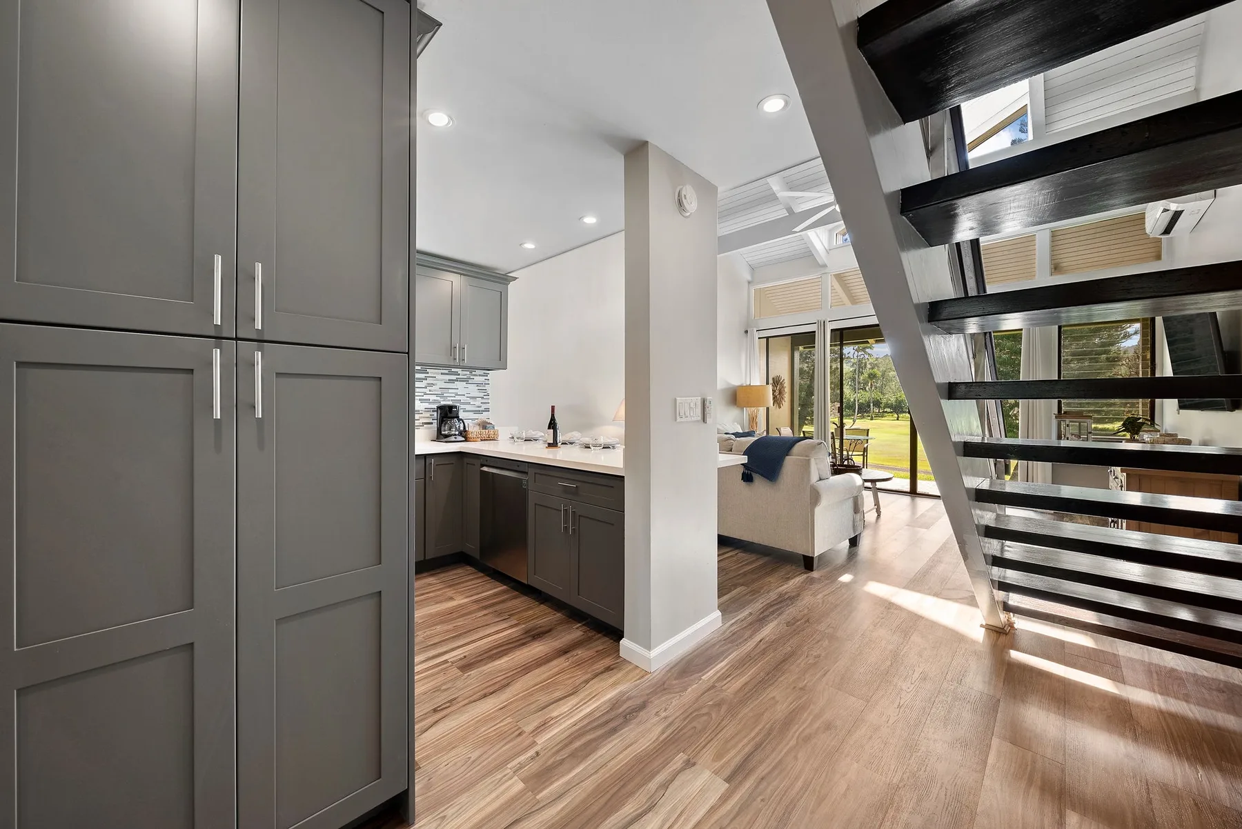 An open-plan kitchen and living area with large windows and wood flooring.