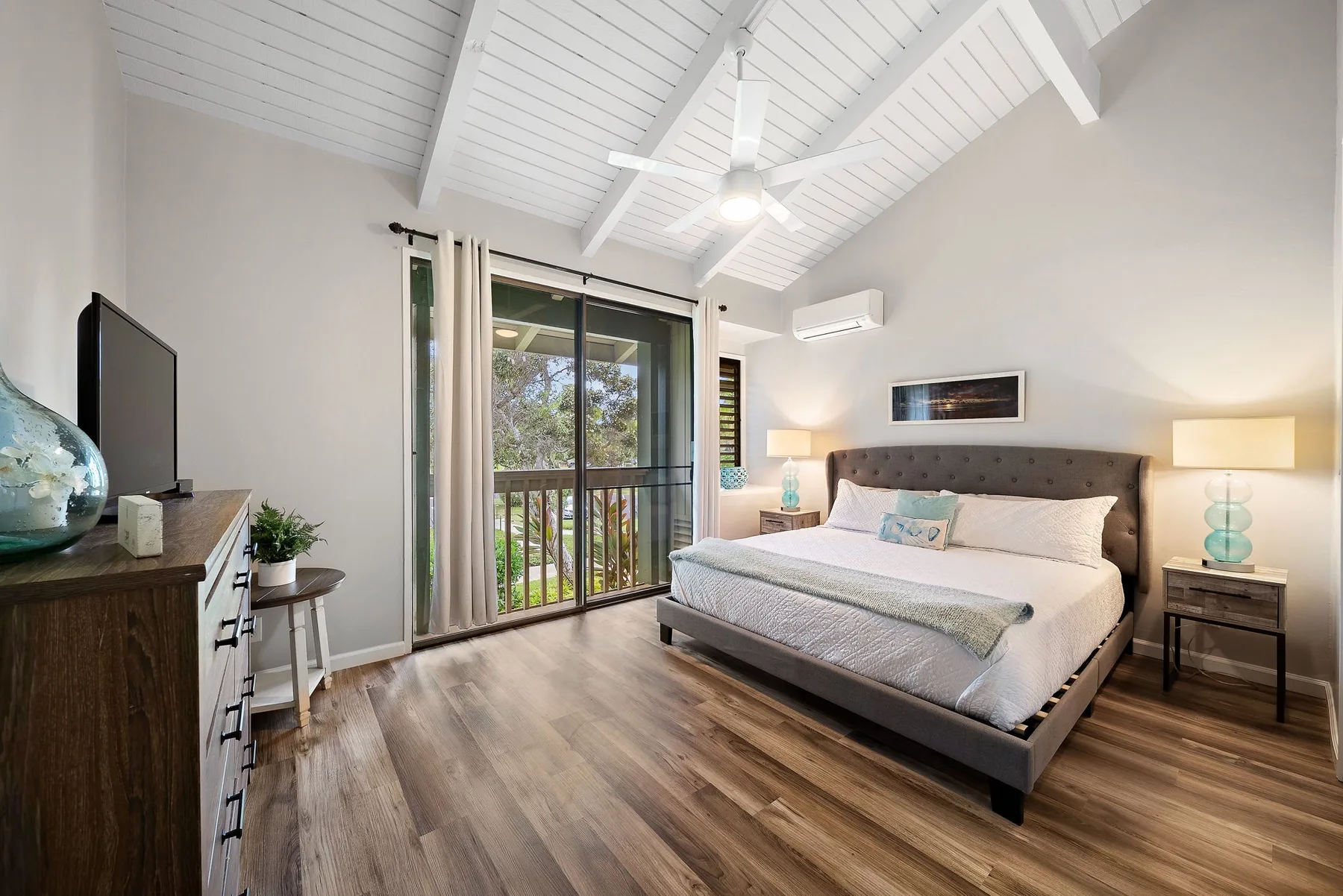 A bright bedroom with a large bed and sliding glass doors opening onto a balcony.