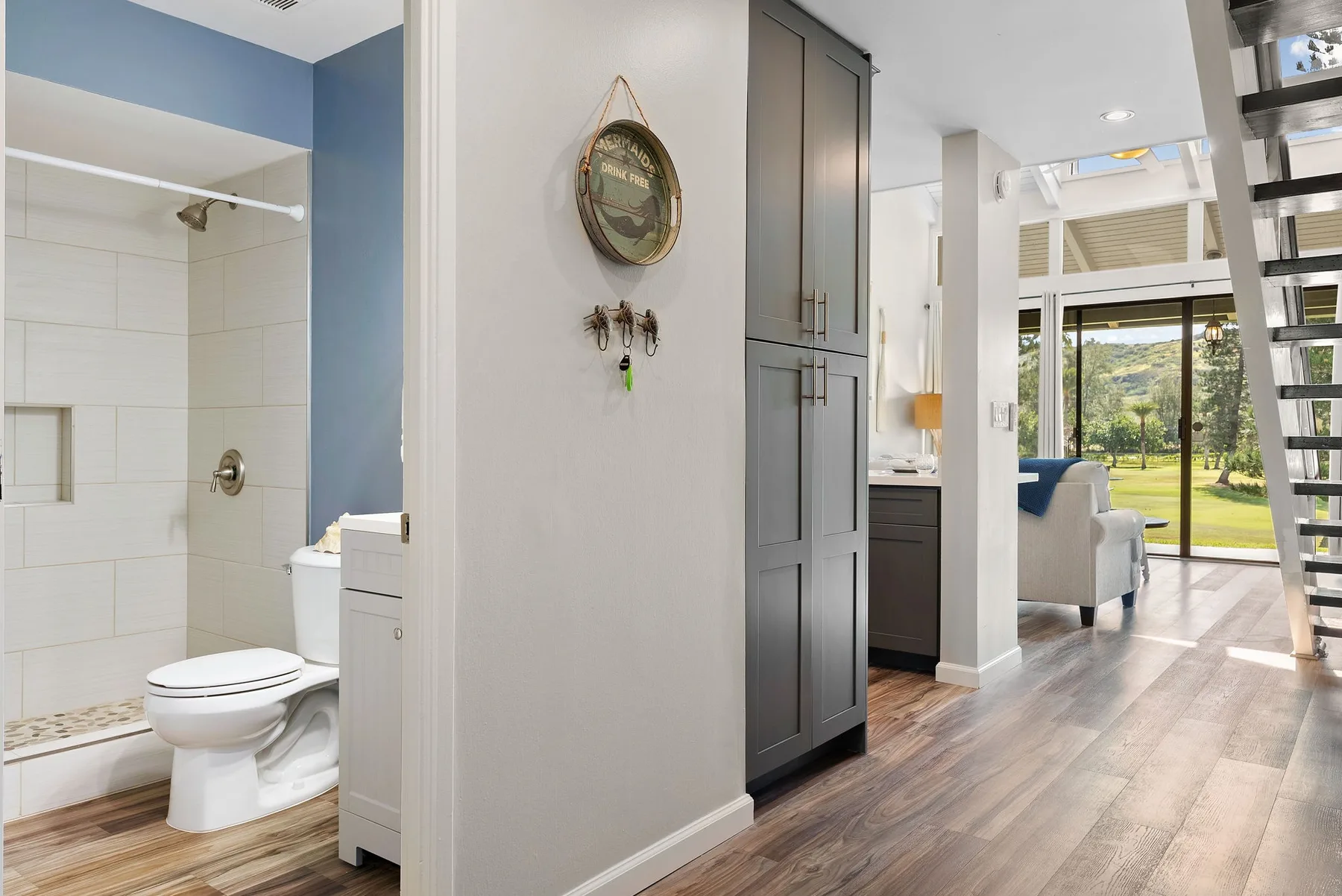 A bathroom opens onto a bright living area with large glass doors.