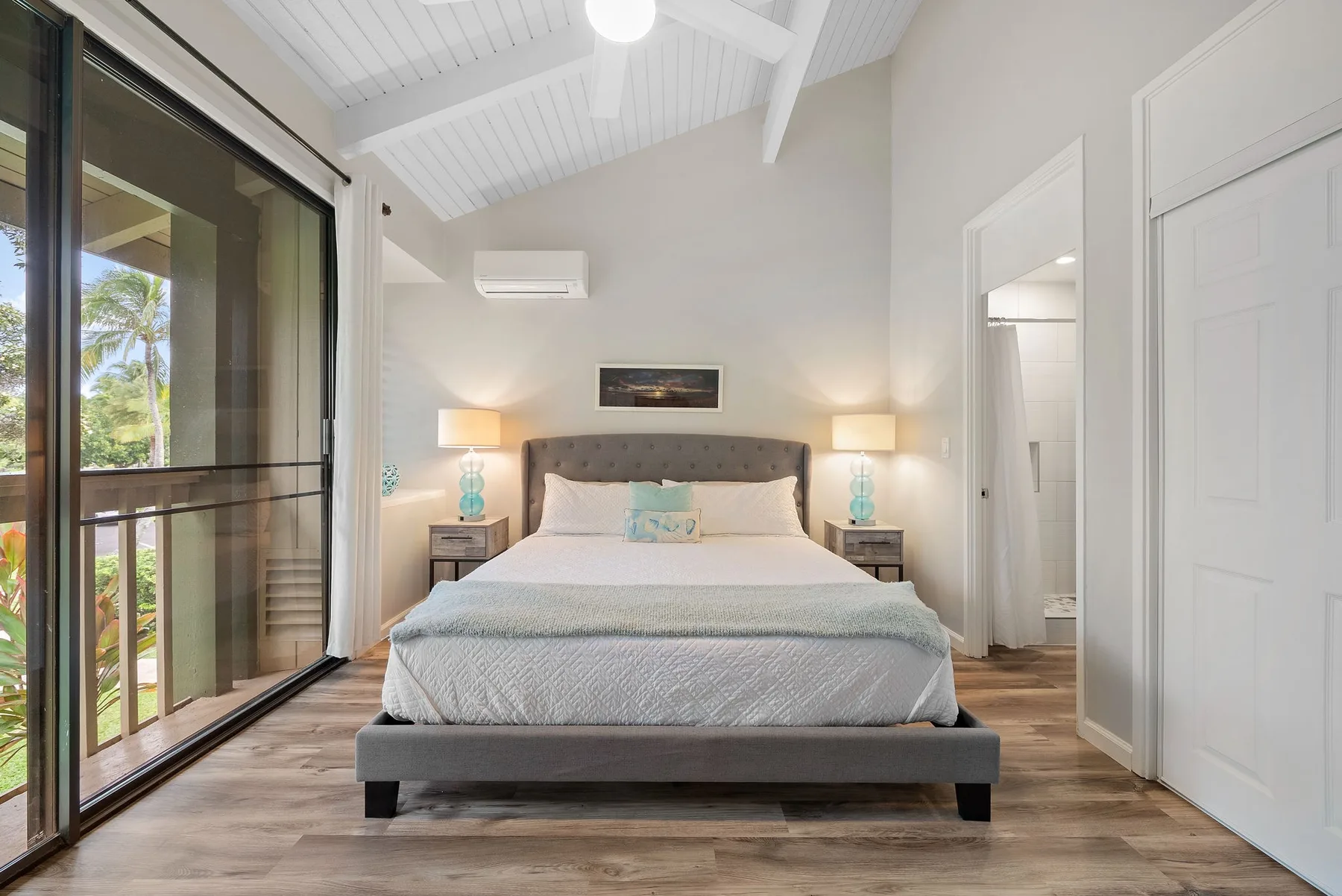 A bedroom with a centered bed, bedside tables, and sliding glass doors.