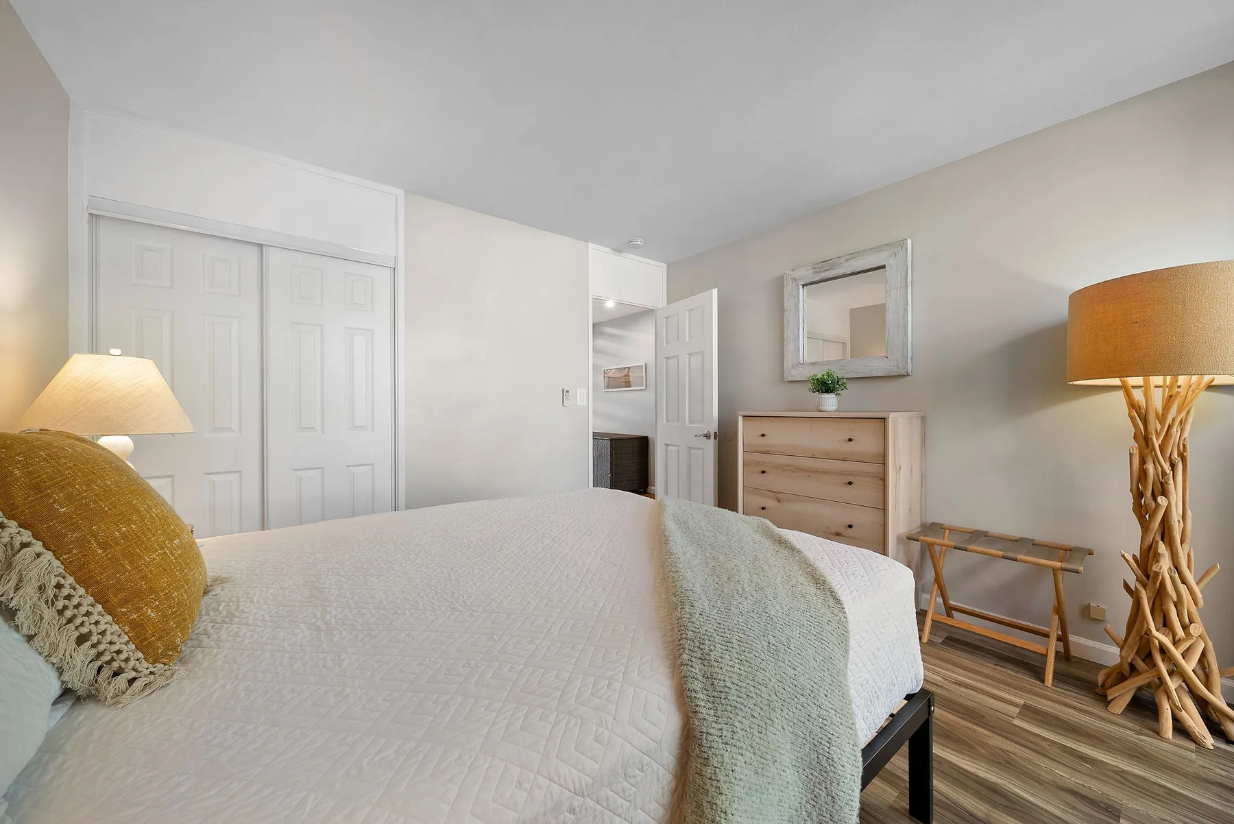 A bedroom with a neatly made bed, dresser, and bedside lamps.