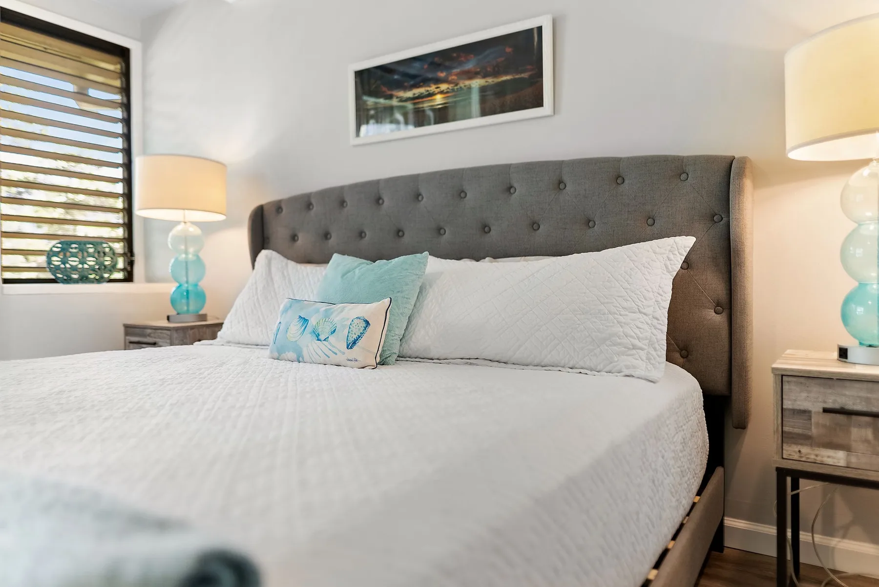 A bedroom with a neatly made bed and a dark upholstered headboard.