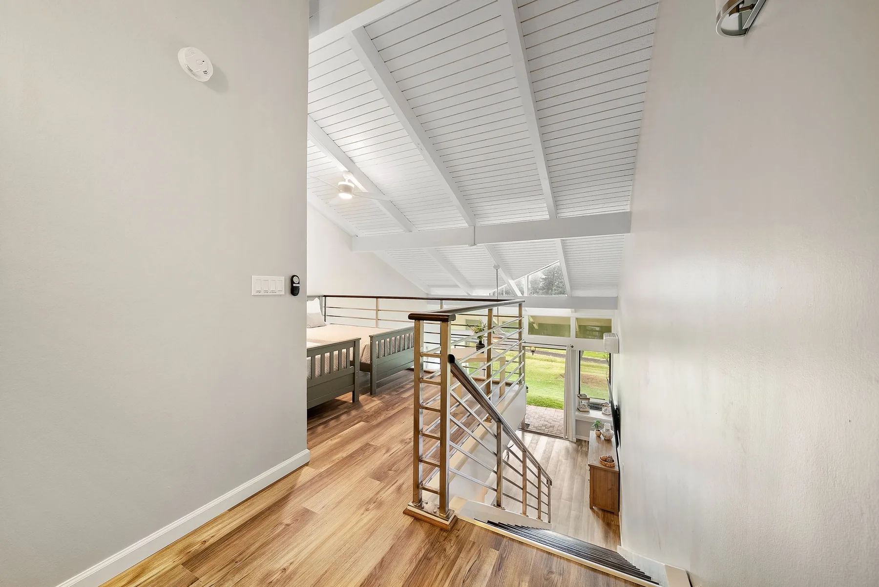 An interior landing overlooks a stairway and a bright living area.