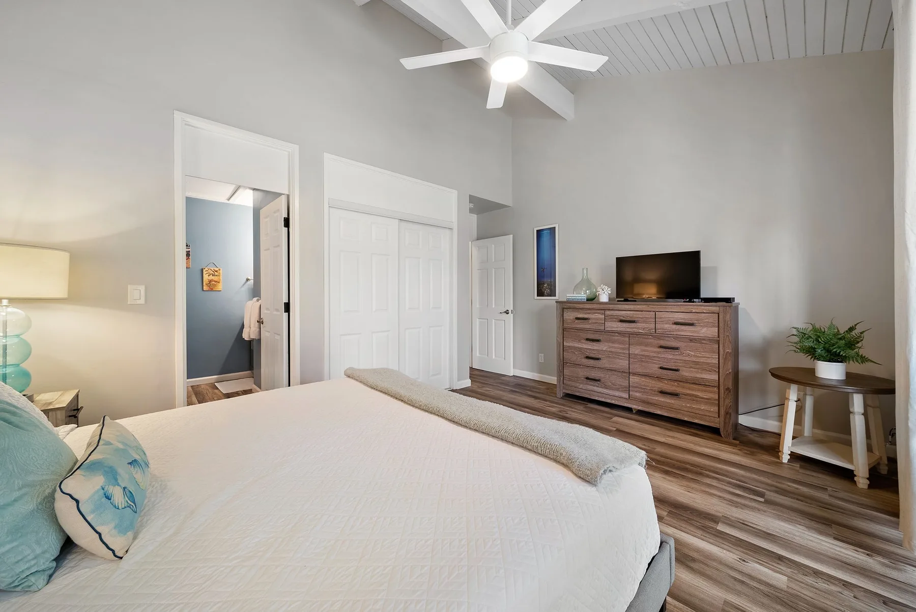 A bedroom with a bed, a wooden dresser, and a ceiling fan.