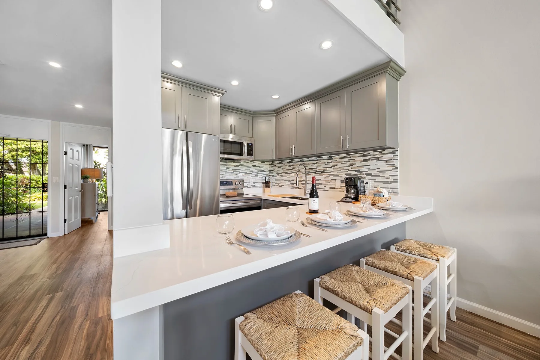 Una cocina luminosa con una isla grande y taburetes preparados para comer.