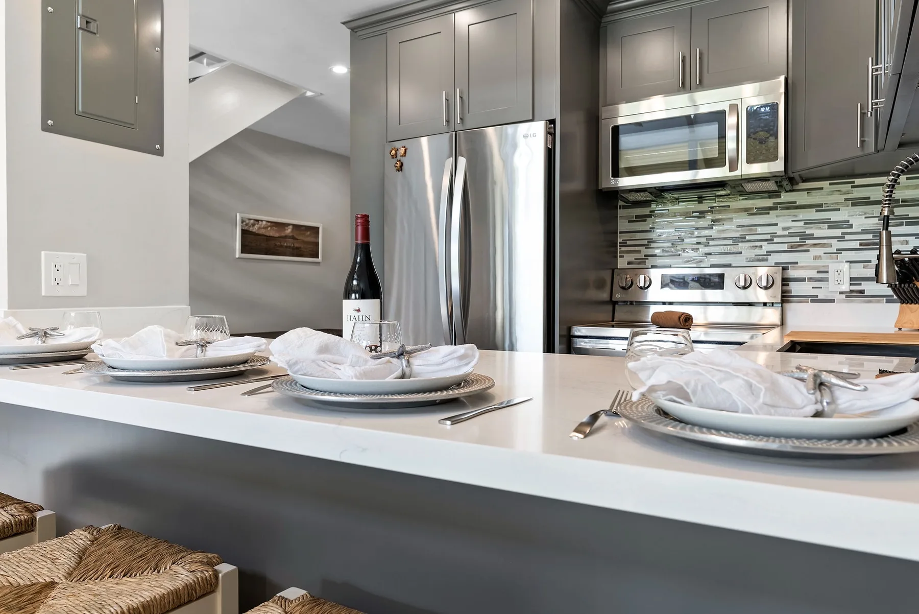 A modern kitchen with a white island set with plates and glassware.