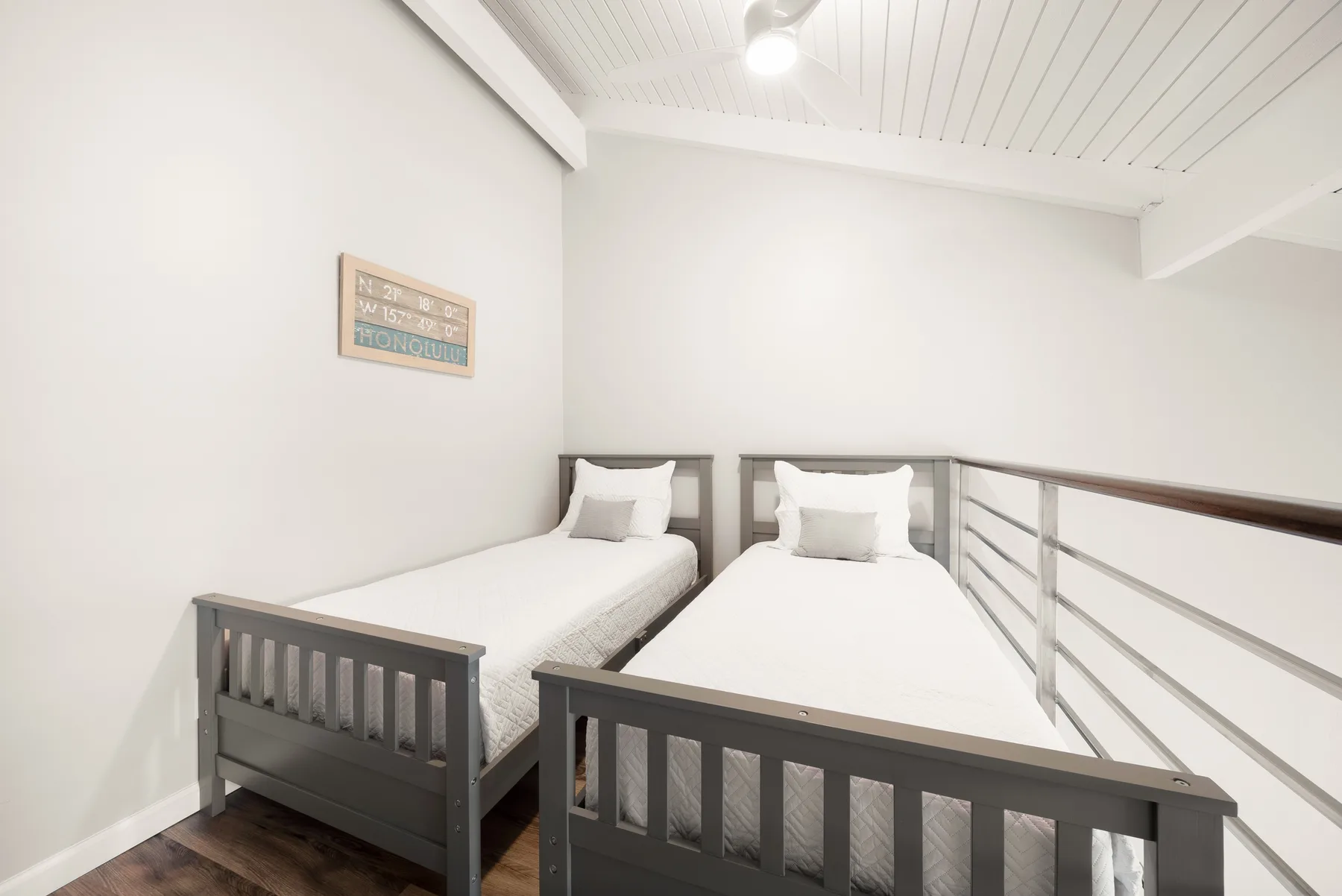 A bright loft bedroom with two single beds beneath a sloped ceiling.