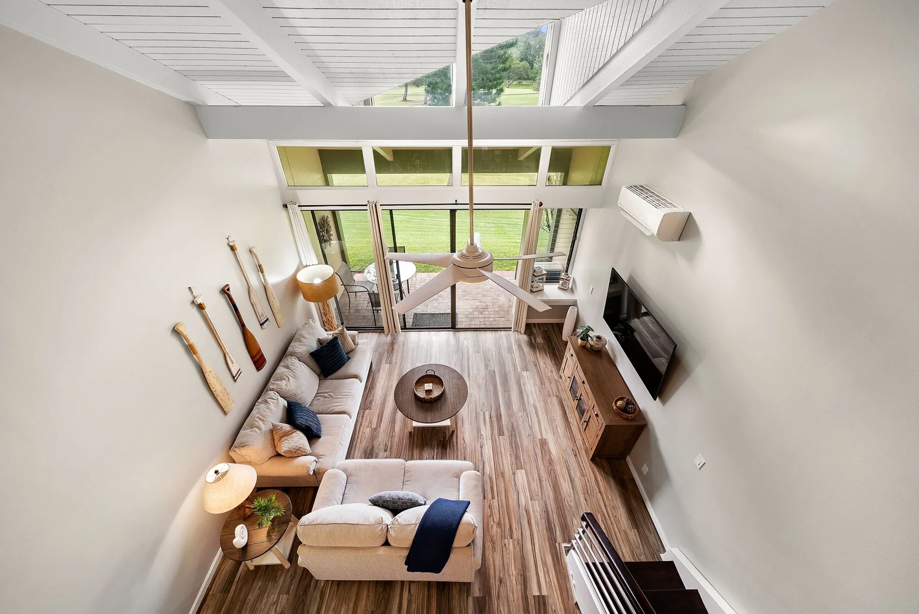 A bright living room with seating, a coffee table, and large windows opening to a patio.
