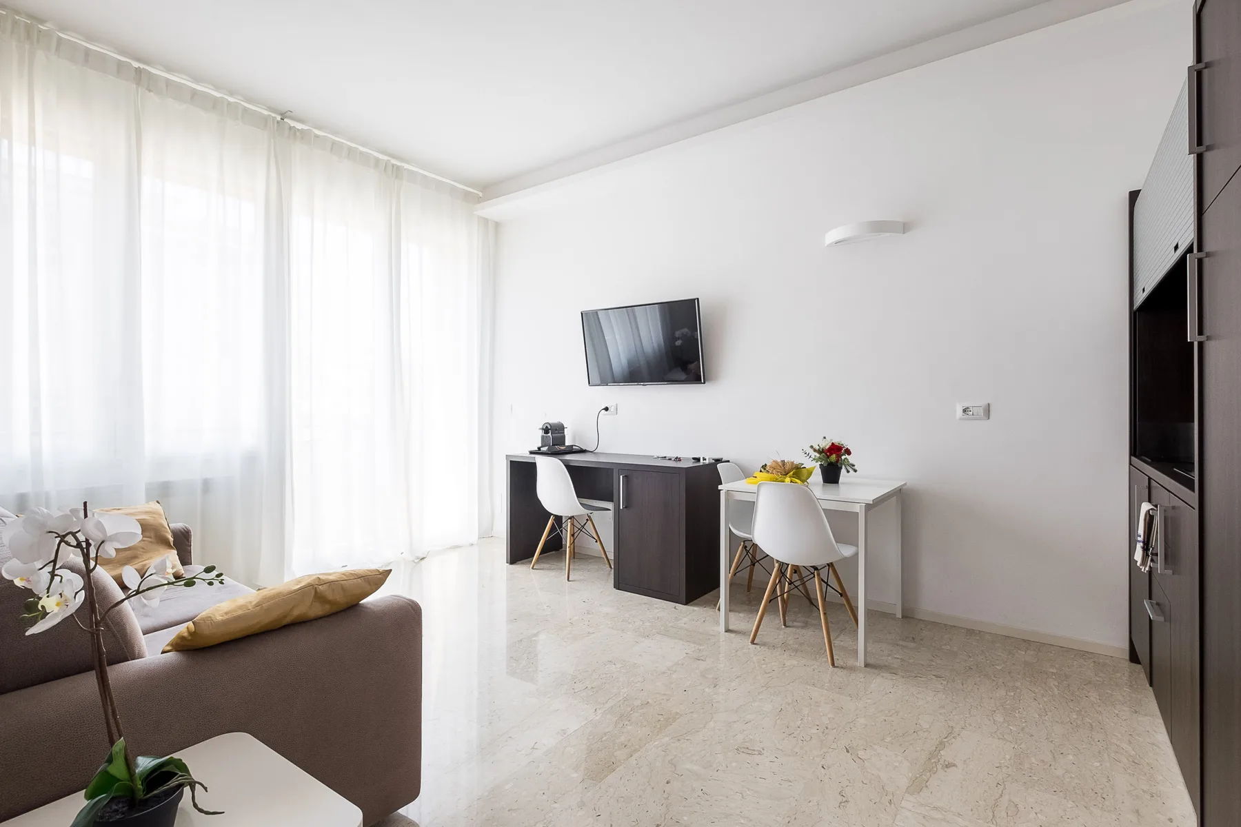 Una sala luminosa con sofá, escritorio y televisor.