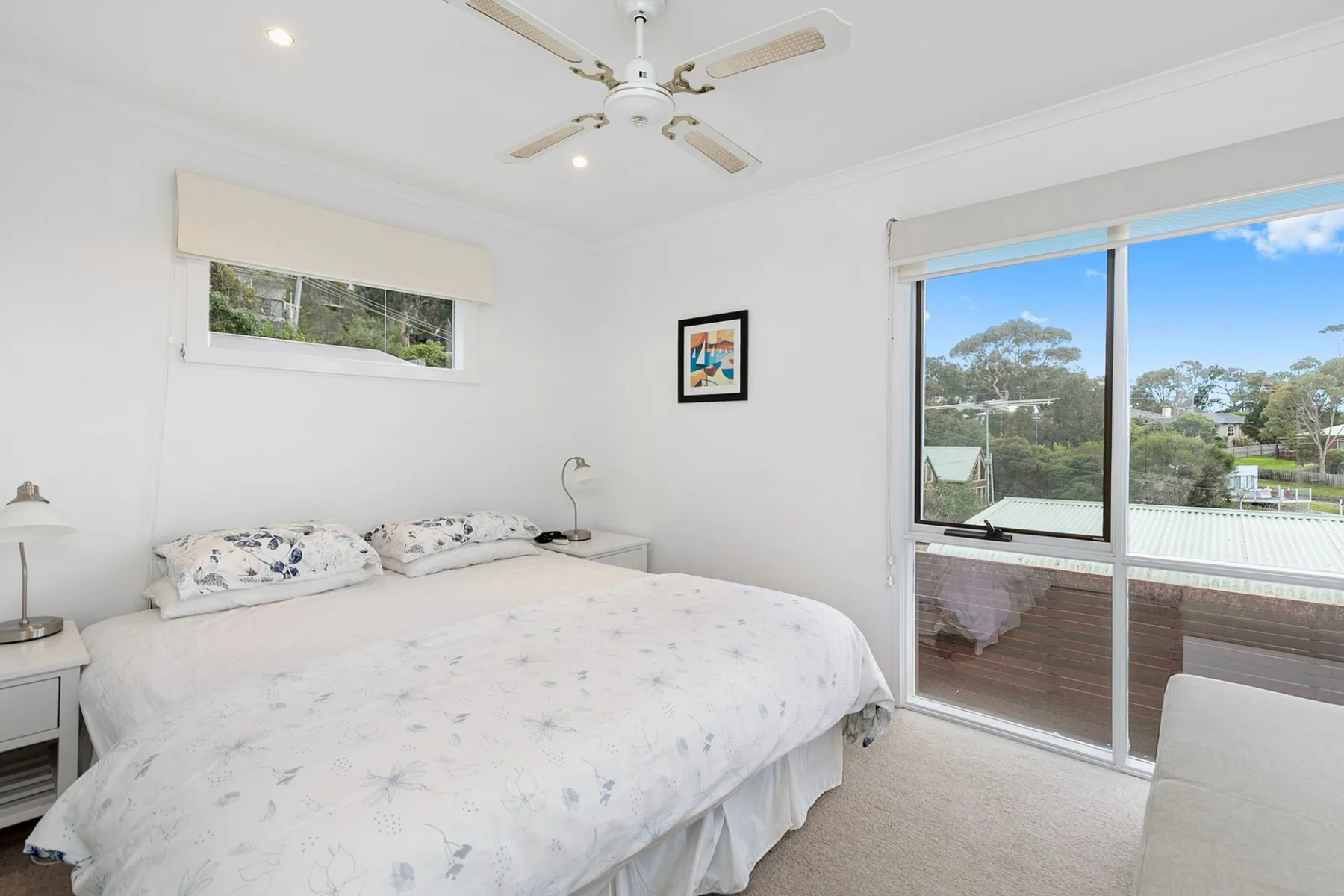 A bright bedroom with a bed beside a sliding glass door.