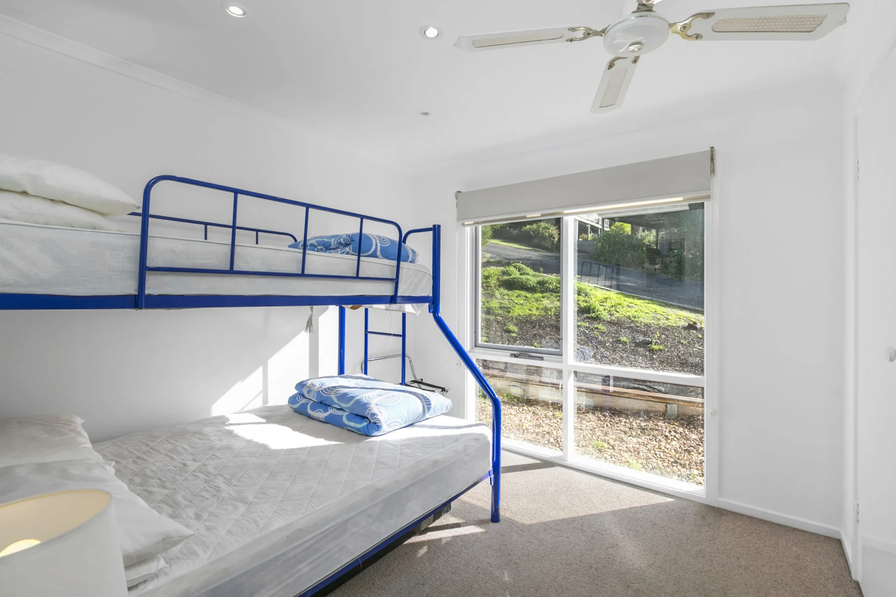 A bright bedroom with bunk beds beside a large window.