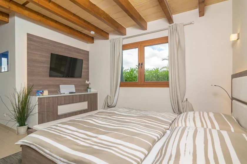 Un dormitorio con una cama, un televisor y una ventana enmarcada por cortinas.