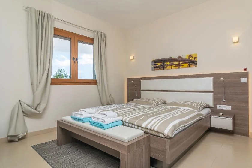 Un dormitorio con una cama doble y toallas dobladas a los pies.