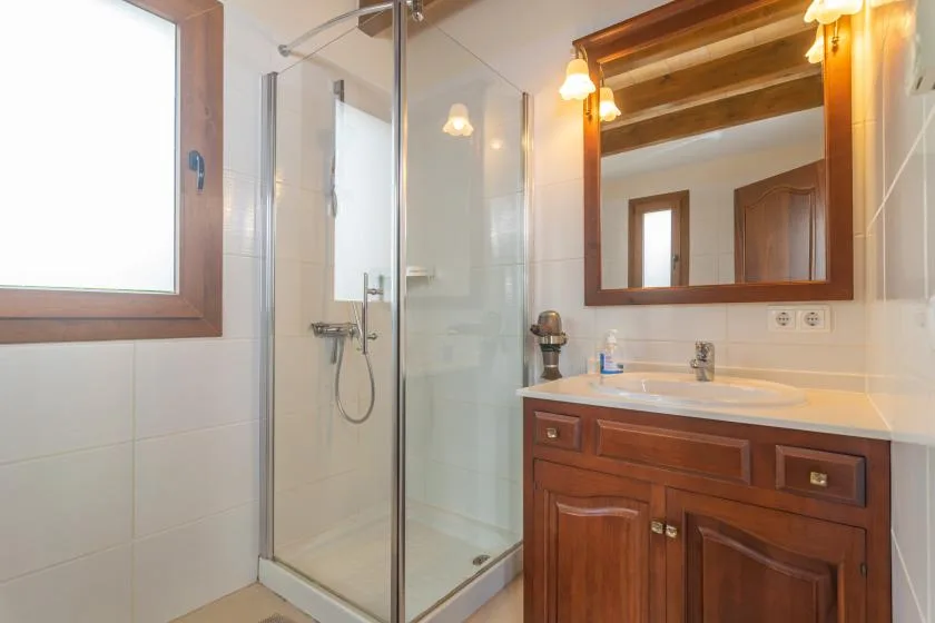 Un baño con una ducha de vidrio y un mueble de lavabo de madera.