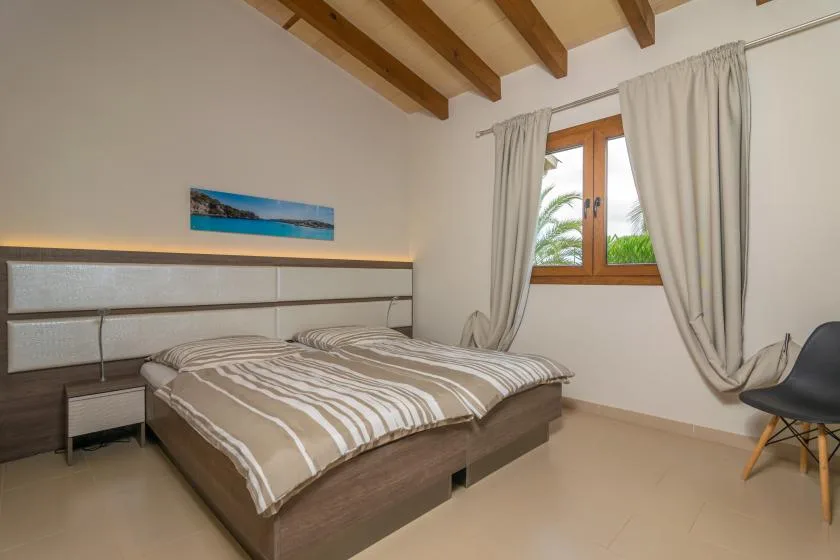 Un dormitorio con una cama doble bajo vigas de madera a la vista.