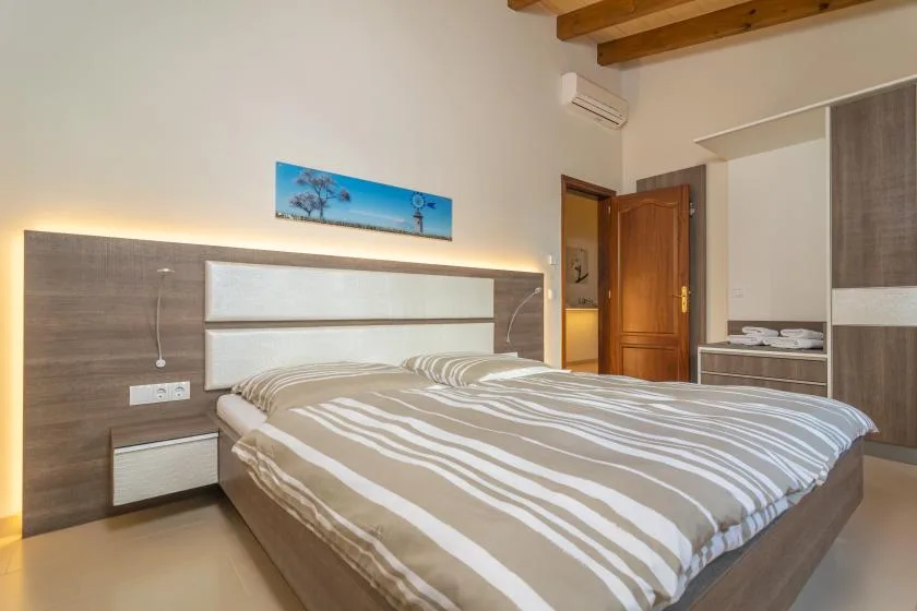 Un dormitorio con una cama grande y ropa de cama a rayas junto a una puerta de madera.