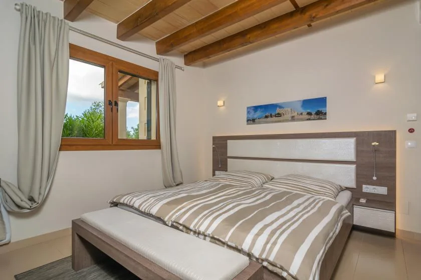 Un dormitorio con una cama doble bajo vigas de madera expuestas.