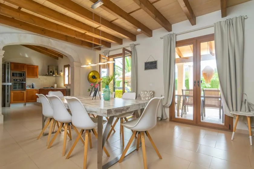 Un comedor con una mesa y sillas junto a puertas de vidrio que dan a un patio.