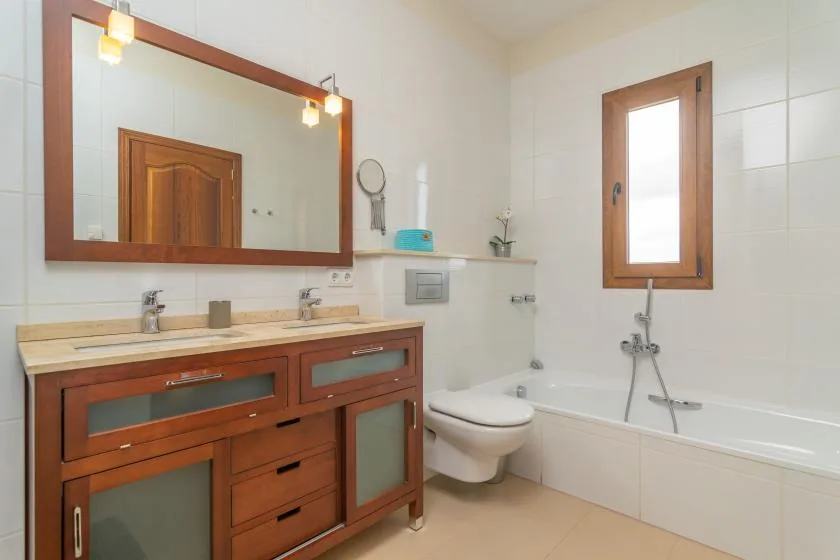 Un baño con tocador de madera, lavabo, inodoro y bañera.