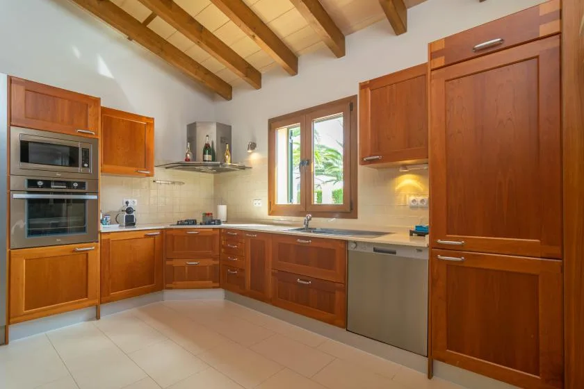 Una cocina de tonos cálidos con gabinetes de madera, una encimera y una ventana.