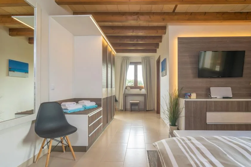 Un dormitorio moderno con una cama, un televisor en la pared y una ventana al fondo.