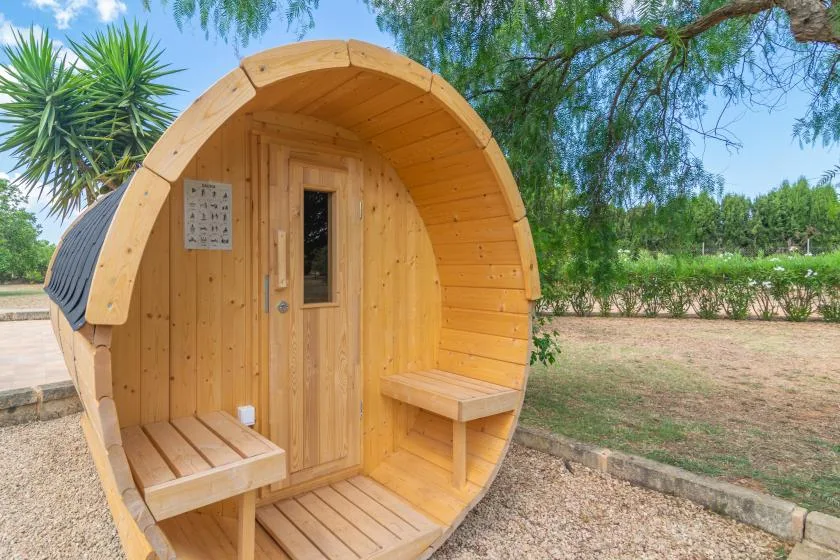 Una sauna de madera al aire libre con entrada redondeada y asientos integrados.