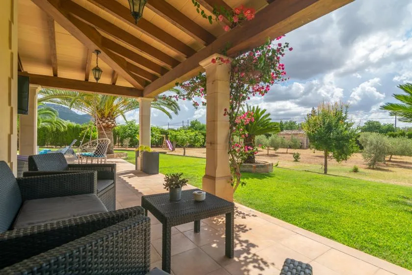 Un patio cubierto con asientos al aire libre da a un jardín verde.