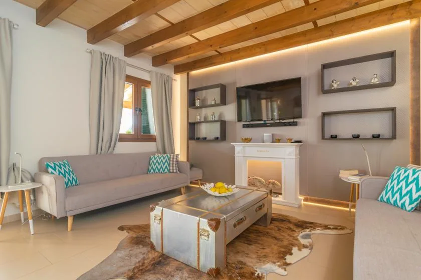 Una sala de estar con asientos, un televisor y una mesa de centro bajo vigas de madera.